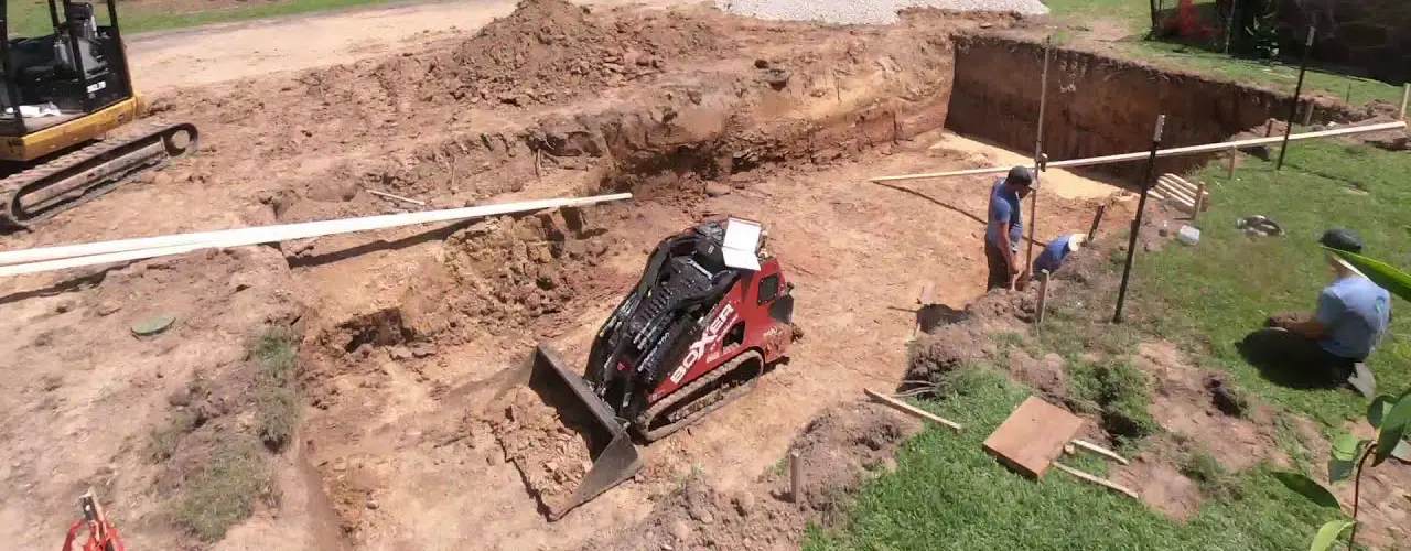 an excavator in a hole digging out dirt for a pool install