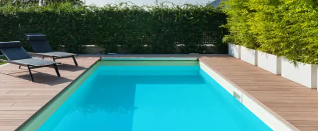 fiberglass rectangular pool with two pool lounge chairs sitting poolside