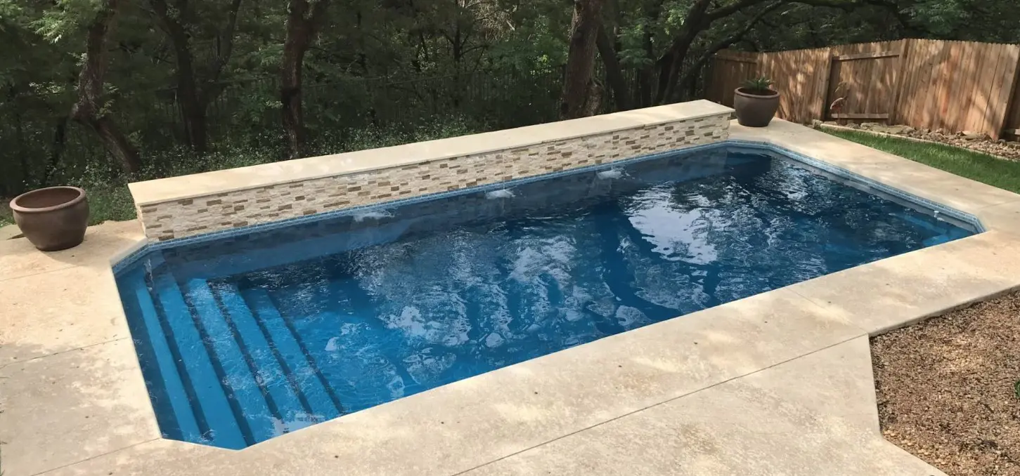 an inground saltwater pool in a wooded backyard